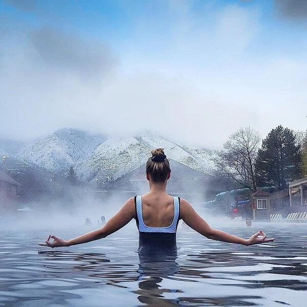 women in yoga pose in hot springs pool