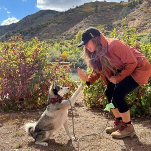 Girl and dog high five on trail, photo by @metropetcarellc