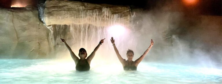 Two friends posing in front of a waterfall at the glenwood hot springs pool