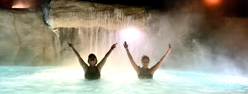 Two friends posing in front of a waterfall at the glenwood hot springs pool