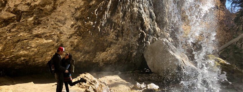 couple in cave behind spouting rock at hanging lake 